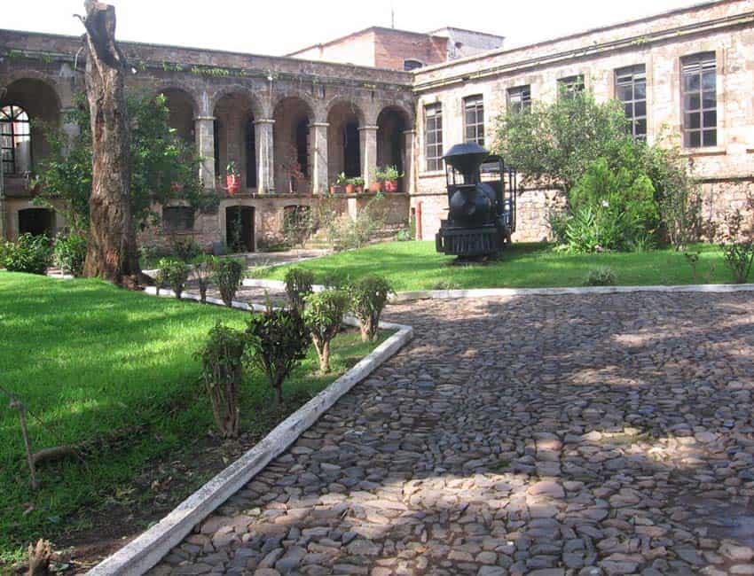 A courtyard garden featuring classical Roman-style arches on the building of the historic Bellavista Textile Factory in Tepic, Nayarit.