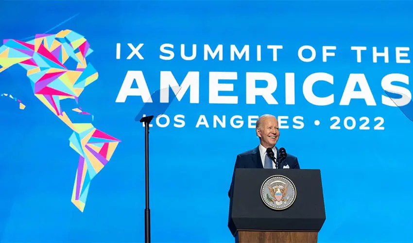 El presidente estadounidense Joe Biden parado en un podio frente a un fondo azul que dice "9na Cumbre de las Américas Los Ángeles 2022"