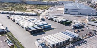 An aerial view outside an industrial park with many containers parked on the paved parking lot.
