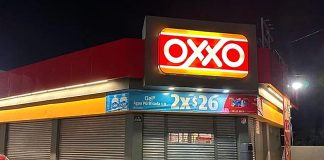 A closed Oxxo store at night with corrugated metal garage style doors covering all doors and windows to the store.