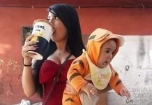 A single mother drinking a beer while holding a baby