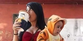 A single mother drinking a beer while holding a baby