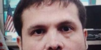 Close-up photo of Joaquin Guzman Lopez in a office with several U.S. flags positioned in various places