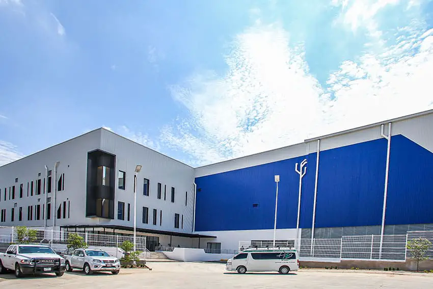 New USI plant in Tonala, Jalisco. Factory building in background with its parking lot in the foreground, with a van and two trucks parked in the lot.