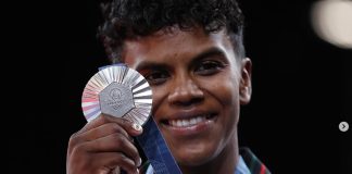 Mexican athlete Prisca Awiti holding the silver medal around her neck in front of her and smiling