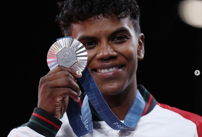 Mexican athlete Prisca Awiti holding the silver medal around her neck in front of her and smiling