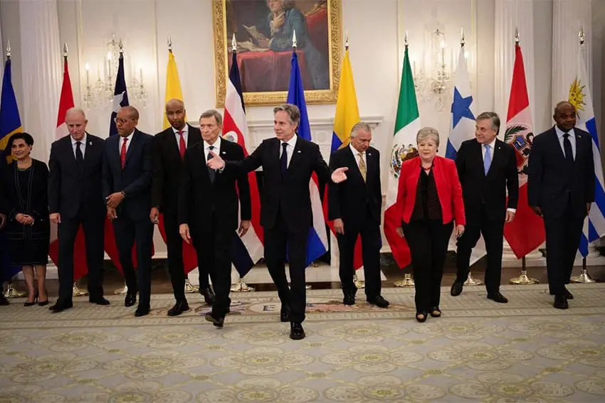 Antony Blinken standing in a horizontal line with foreign ministers of member countries of the Americas Partnership For Economic Prosperity. Blinken is at the center of the line with his palms outstretched