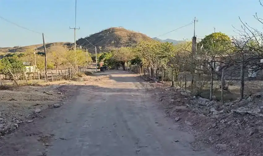 A view of a rural dirt road with fences and houses, where El Mayo Zambada was born.