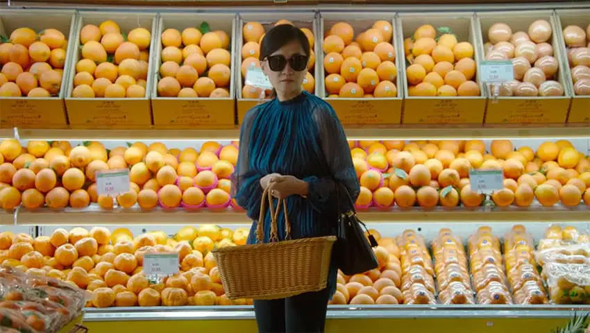 A woman stands in front of fruit in a supermarket in a shot from "Brief History of a Family," a GIFF film.