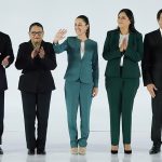 Sheinbaum stands on a white stage with her newly announced cabinet appointees.