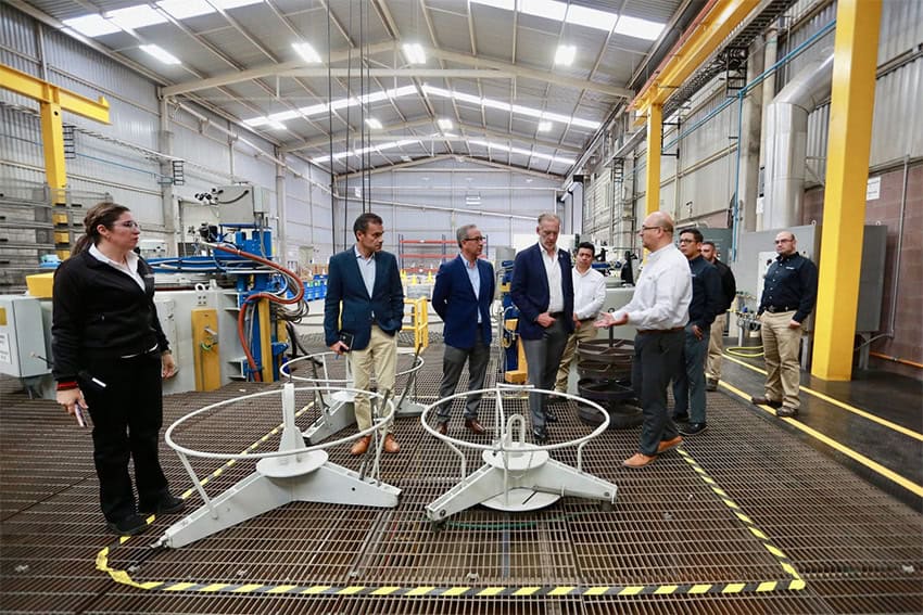 Marco Antonio del Prete and other Querétaro officials look at machinery in an aerospace industry factory.