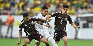 Two Mexican soccer players in red uniforms go after an Ecuadorian player in white with the ball, before Mexico was eliminated from the Copa América.