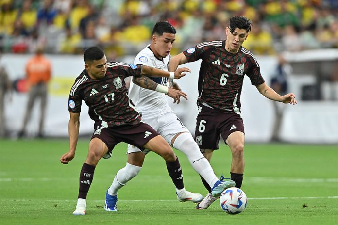 Two Mexican soccer players in red uniforms go after an Ecuadorian player in white with the ball, before Mexico was eliminated from the Copa América.