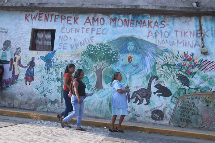 Residents of the Nahua town Cuentepec in Morelos walk by a multi-lingual mural.