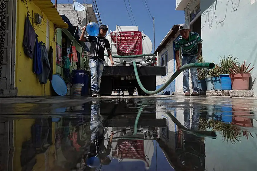 A water truck passes through a narrow street in Iztapalapa making deliveries.