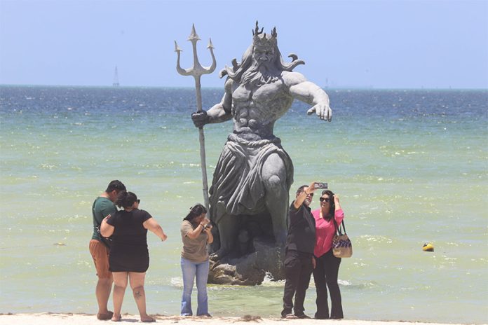 Visitors take photos near a statue of Poseidon in the ocean outside Progreso, Yucatán