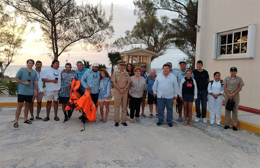 The fishing buddies pose with family and Navy officials on land after their rescue.