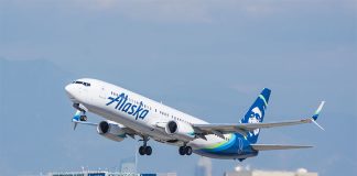 An Alaska Airlines plane taking off over the Los Angeles city skyline