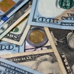 Image of US currency bills of various denominations in a pile around a single Mexican peso coin, which hit a a 4-month high on Friday