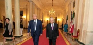 AMLOAMLO and Donald Trump walk down a red carpet in an elegant hallway. and Donald Trump walk down a red carpet in a long corridor.