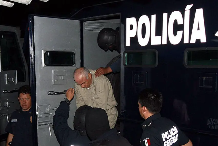 Jean Succar Kuri being escorted out of a police paddy wagon by several Mexican police