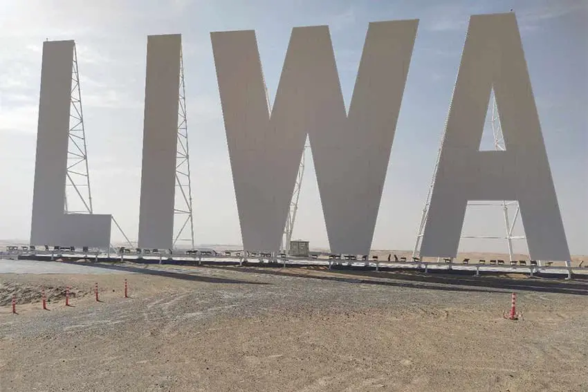 Landmark sign for the Liwa municipality in the United Arab Emirates standing on flat desert land.