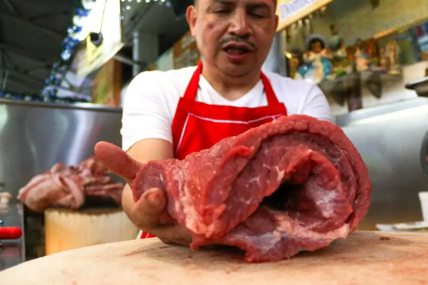 A man with a piece of meat on a butcher's block