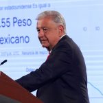 President López Obrador stands in front of a presentation on the dollar-peso exchange rate.