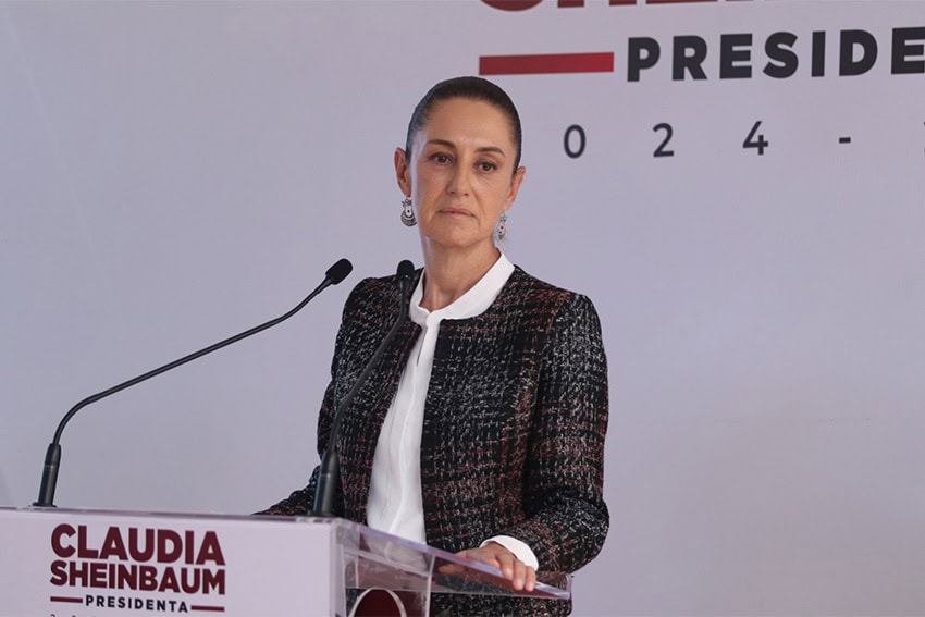 Mexico's president-elect Claudia Sheinbaum standing at a podium saying "Claudia Sheinbaum, Presidenta," She has a grim expression