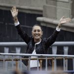 Claudia Shienbaum waves her hands in the air to crowds in Mexico City's Zocalo behind metal security barriers