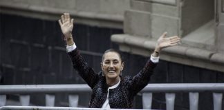 Claudia Shienbaum waves her hands in the air to crowds in Mexico City's Zocalo behind metal security barriers