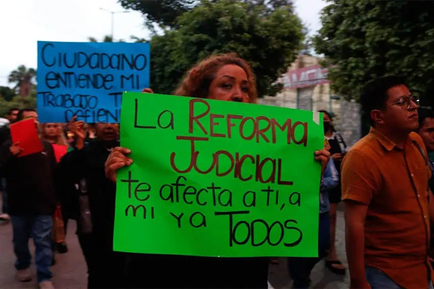 Jueces mexicanos en Guerrero, México, en una marcha de protesta contra un controvertido proyecto de reforma judicial, sosteniendo carteles en español