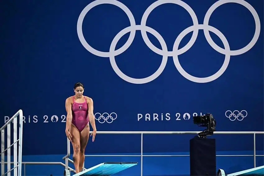 Mexican diver Aranza Vázquez on a diving board at the Paris Olympics, preparing to take a dive