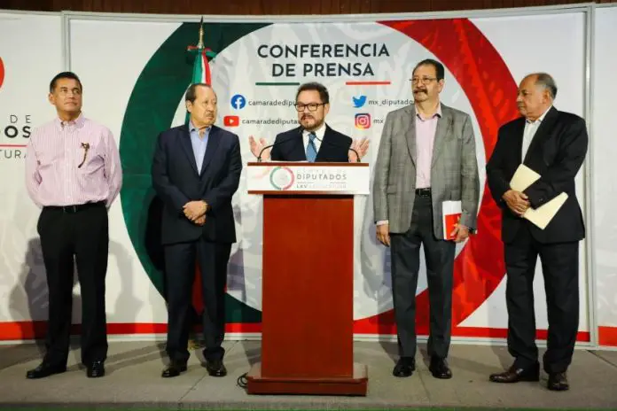 Morena party leader Ignacio Mier at a podium announcing changes to Mexico's proposed judicial reform, shortly before a court workers strike.