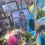 Framed photos of soldiers killed fighting for Ukraine standing among little flags of different nations