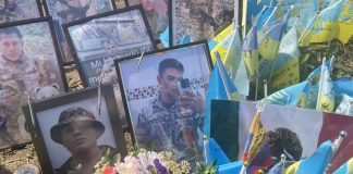 Framed photos of soldiers killed fighting for Ukraine standing among little flags of different nations