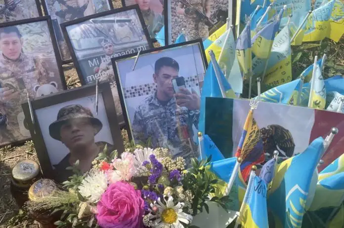 Framed photos of soldiers killed fighting for Ukraine standing among little flags of different nations