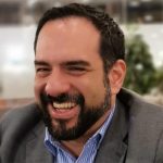 Manuel Guerrero sitting and smiling, wearing a men's suit