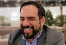 Manuel Guerrero sitting and smiling, wearing a men's suit