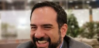 Manuel Guerrero sitting and smiling, wearing a men's suit
