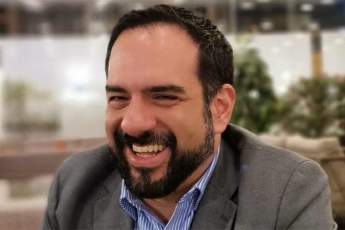 Manuel Guerrero sitting and smiling, wearing a men's suit