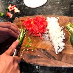 Hands chopping tomato, onion and jalapeño