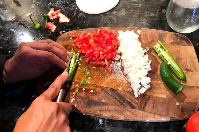 Hands chopping tomato, onion and jalapeño