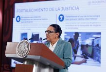 Rosa Icela Rodriguez standing at a podium behind a large display screen that says "fortalecimiento de la justicia"