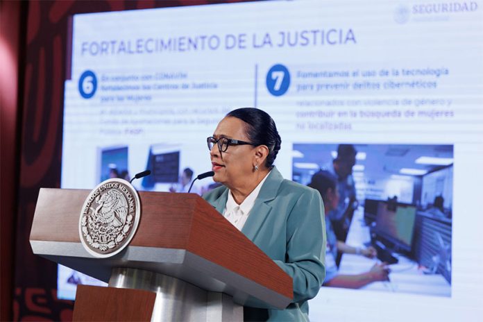 Rosa Icela Rodriguez standing at a podium behind a large display screen that says 