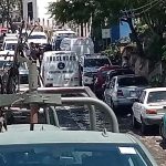 A soldier of the Mexican army standing in the bed of an armored pickup truck behind a traffic jam of other federal and military vehicles blocking a street in Taxco