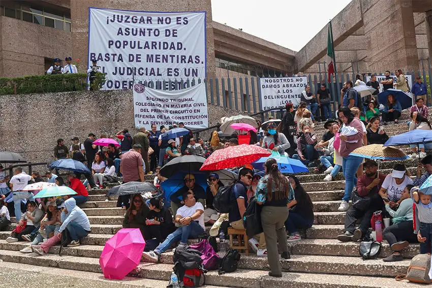 Federal judicial workers sit on the Mexico City court steps with signs protesting the judicial reform.