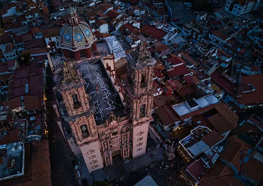 Taxco, Guerrero's parish church and the city downtown seen from above at twilight.