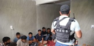 A police officer stands in front of the migrants who were held hostage in Oaxaca.