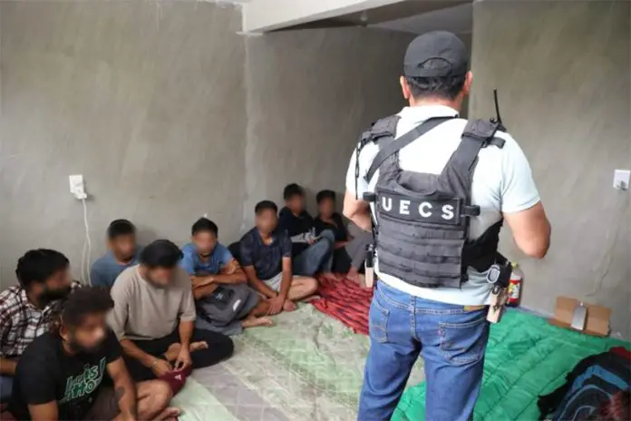 A police officer stands in front of the migrants who were held hostage in Oaxaca.